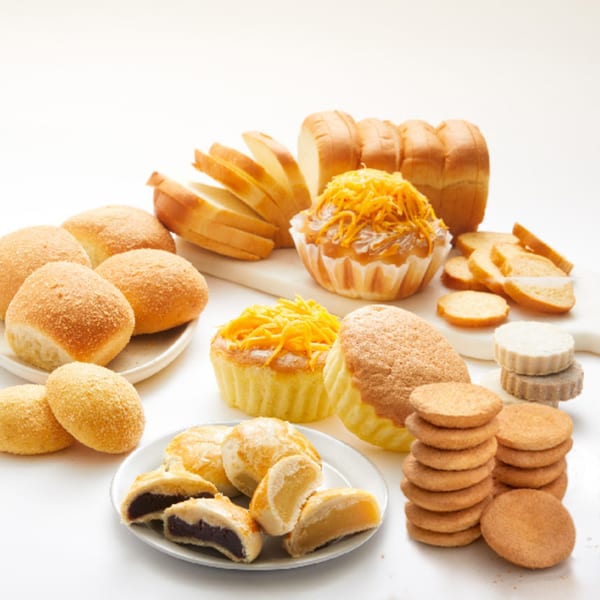 Assortment of Goldilocks Filipino baked goods, including pandesal, mamon, sliced bread, and cookies.