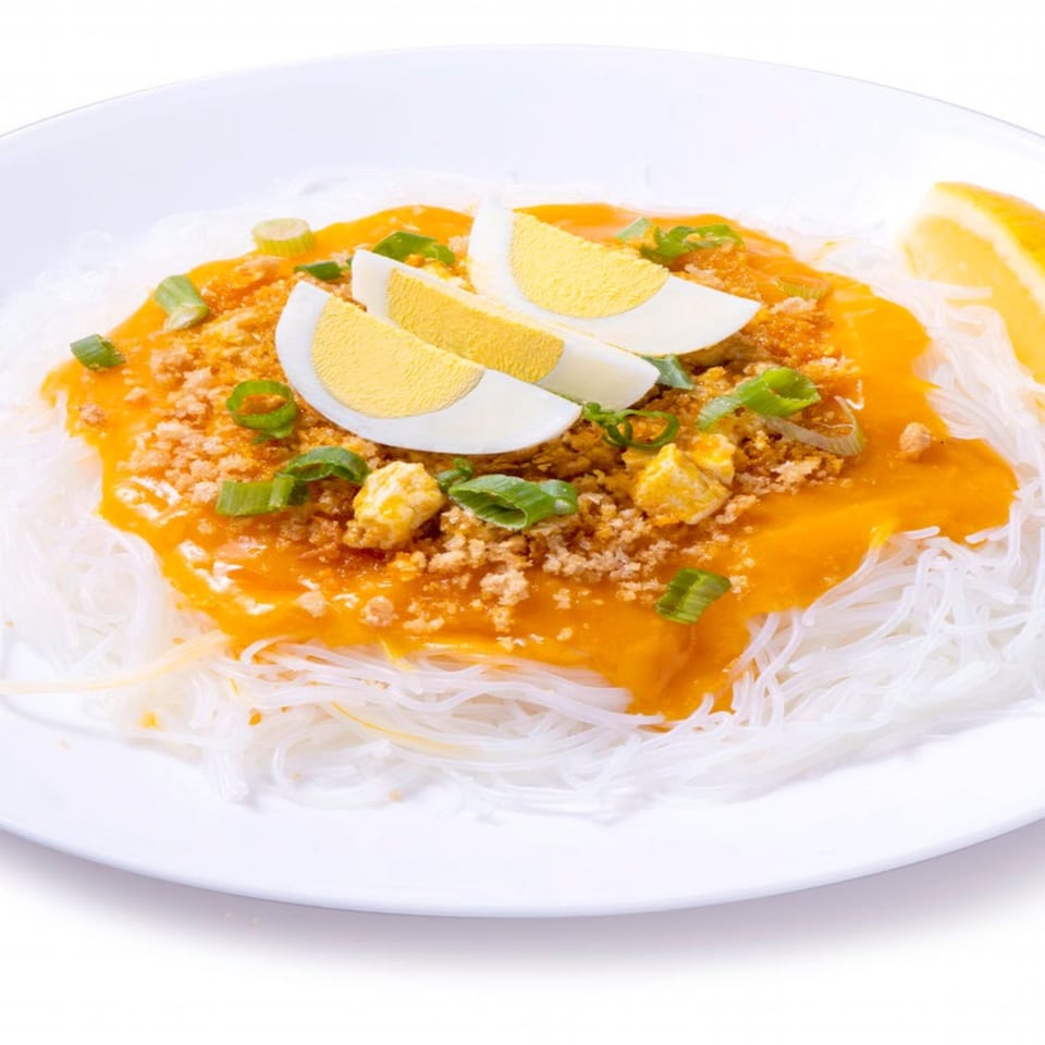 Pancit Palabok from Goldilocks, with orange sauce, crushed chicharon, sliced eggs, and green onions.