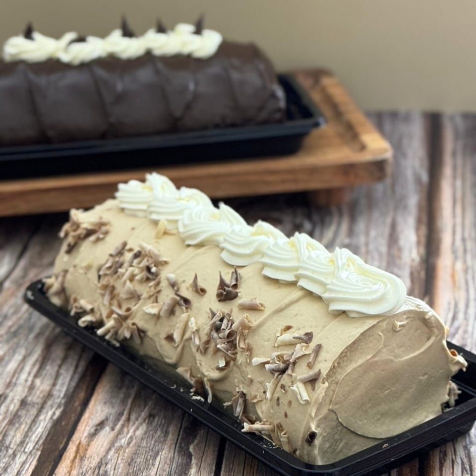 Two Goldilocks mocha and chocolate cake rolls with whipped cream and chocolate shavings.